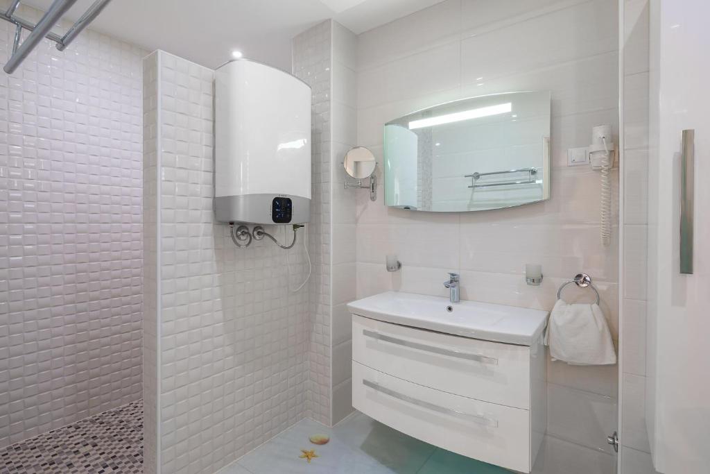 biała łazienka z umywalką i lustrem w obiekcie Appartements Banya w Korčuli