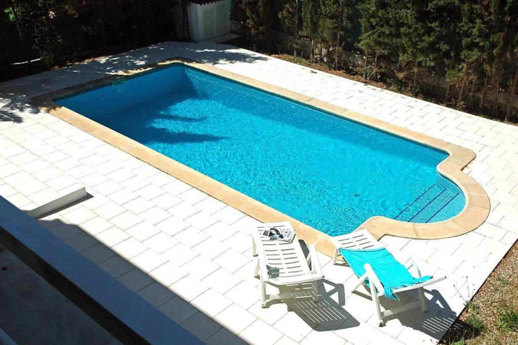 a swimming pool with two lawn chairs and a swimming pool at Villa with pool, 200m from beach in Cala Blanca
