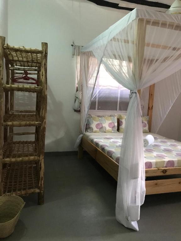 パジェにあるHakuna Matata Guest Houseのベッドルーム1室(天蓋付きベッド1台、はしご付)