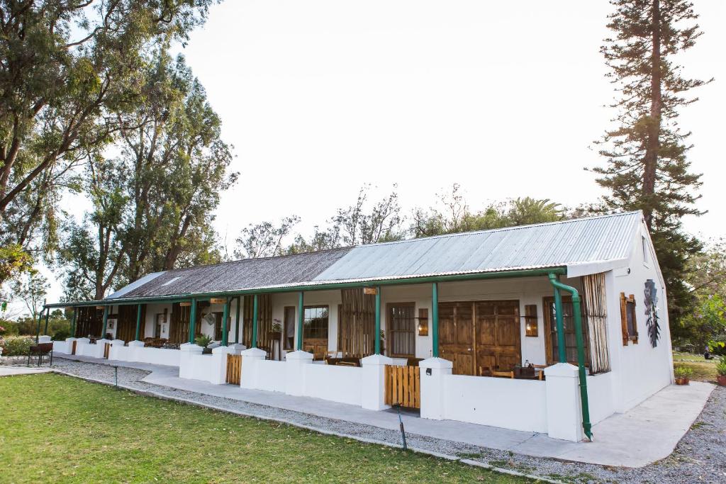 a small white building with trees in the background at Schaftplaas Cottages in Langebaanweg