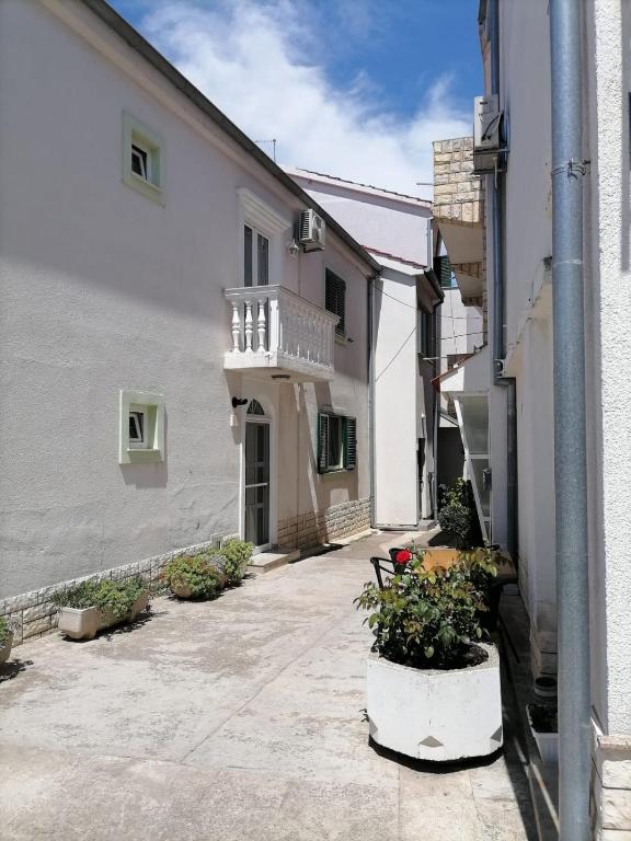 an alley with a white building and some plants at Apartmani Gajeta in Biograd na Moru