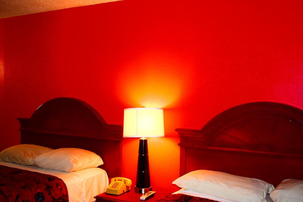 - une chambre rouge avec deux lits et une lampe dans l'établissement Economy Inn Little Rock, à Little Rock