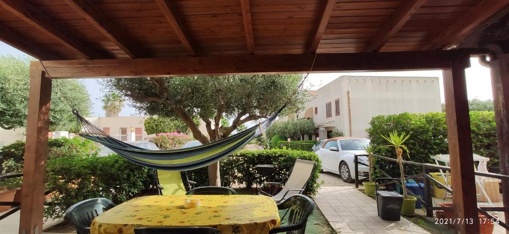 a hammock on a patio with a table and a car at Kiterhouse in Case Milazzo