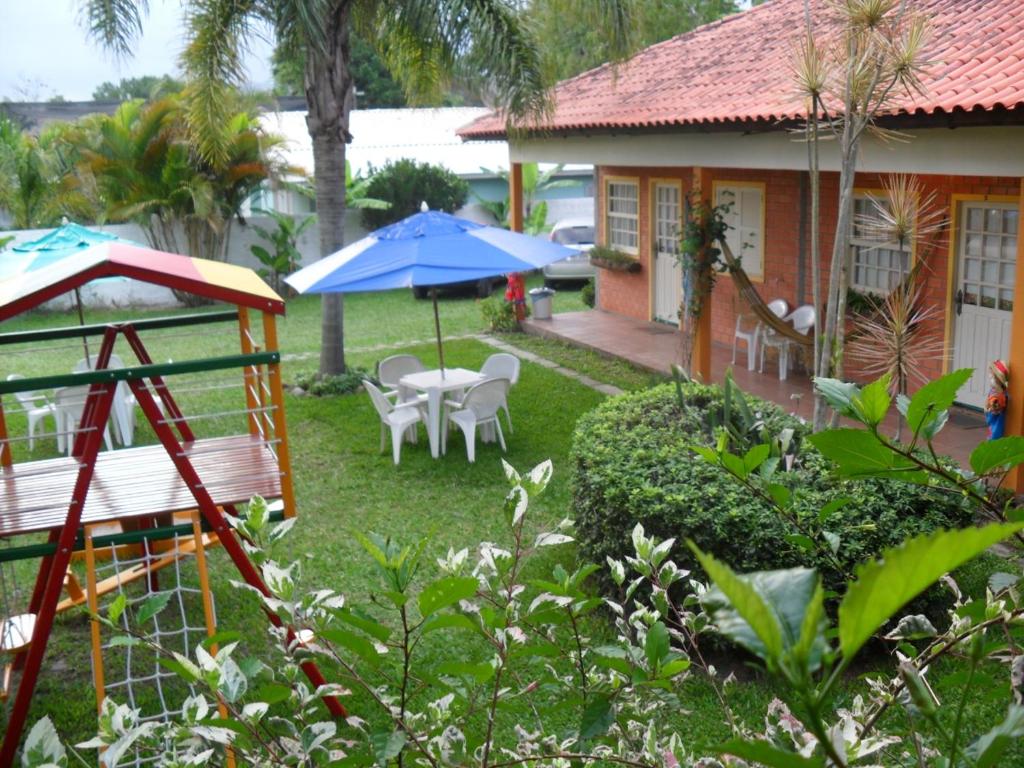 une maison avec une table, des chaises et un parasol dans l'établissement Pousada Albergo Dei Fiori, à Imbituba