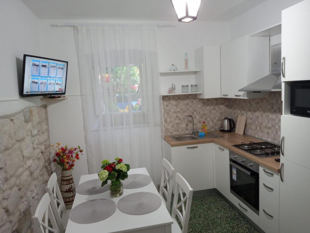 uma cozinha com uma mesa e cadeiras e uma televisão em Apartman Marin - Viganj em Viganj