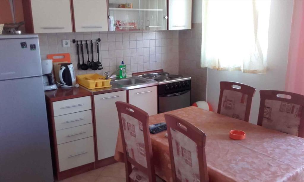 a kitchen with a table and a sink and a refrigerator at Lopar Apartment 3 in Lopar