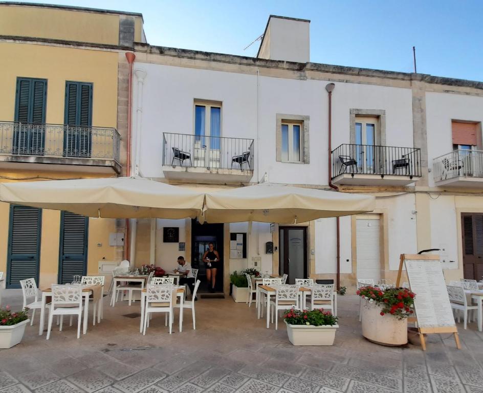 a patio with tables and chairs and umbrellas in front of a building at Mediterraneo Camere in Otranto