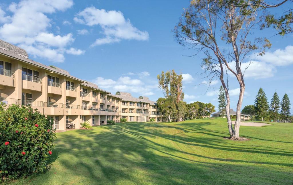 un edificio de apartamentos con un árbol en el patio en Paniolo Greens Resort en Waikoloa