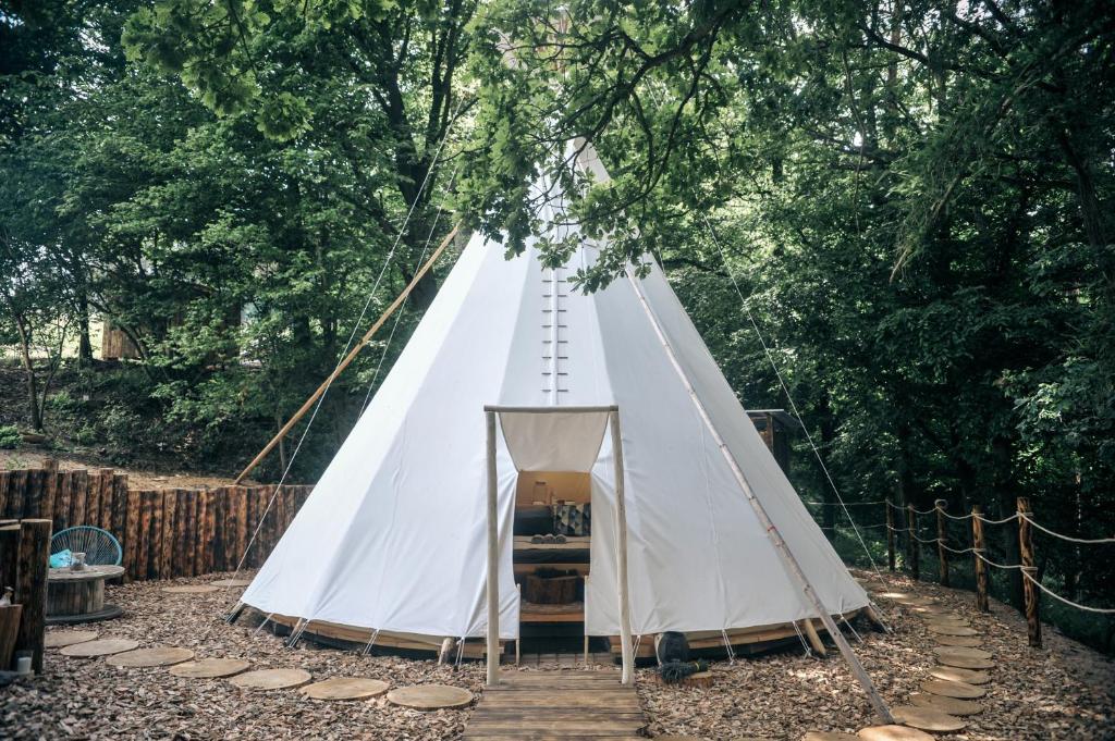 a white teepee tent in the middle of a forest at Glamping Nad Meandry in Unhošť