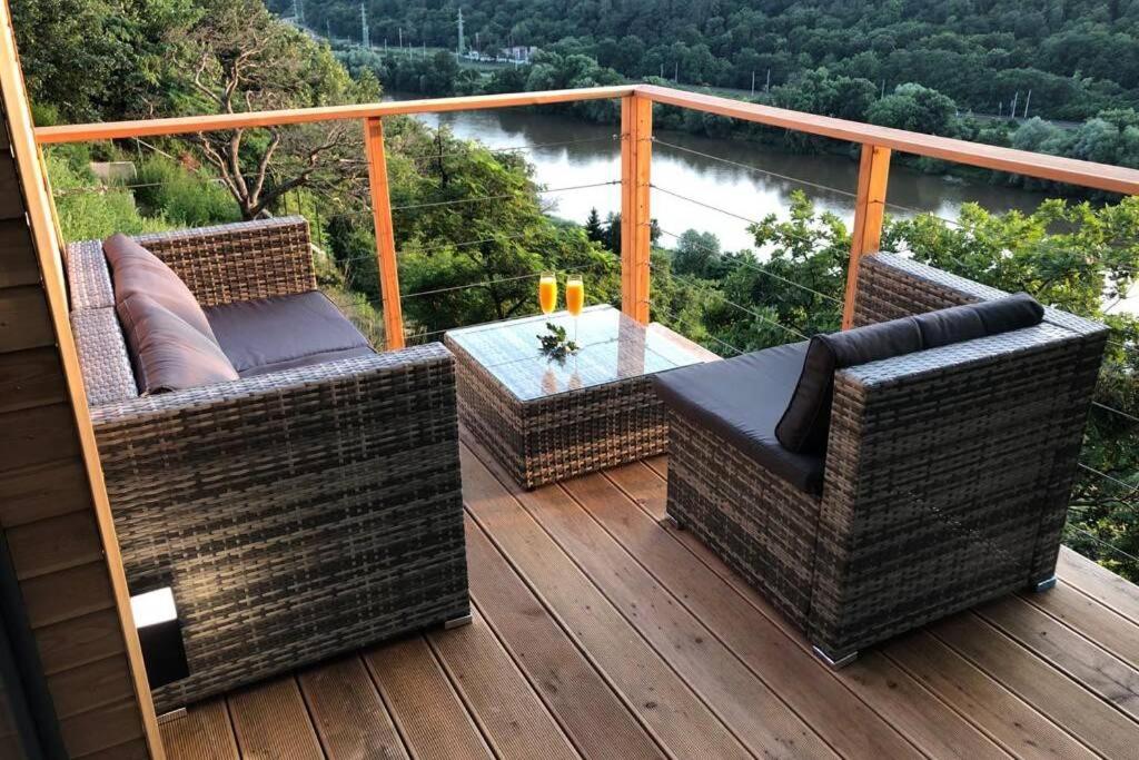 Un balcón con sillas de mimbre y una mesa en una terraza. en Chatka - C - Vyhlídka nad řekou, en Zdiby