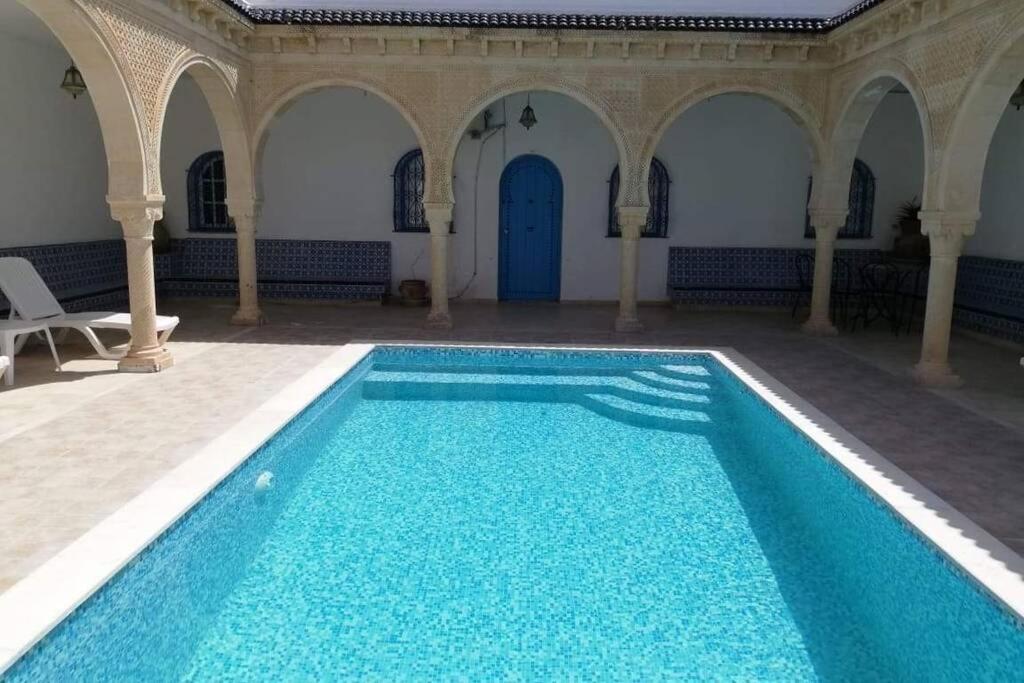 - une piscine d'eau bleue dans un bâtiment dans l'établissement Maison typiques (houche) avec piscine, à Houmt Souk