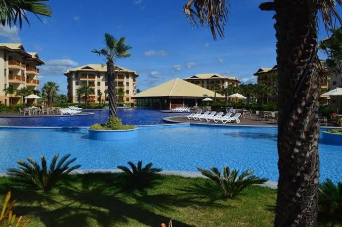 a swimming pool at a resort with chairs and palm trees at VG SUN CUMBUCO 2 quartos - B2, apto 205 in Cumbuco