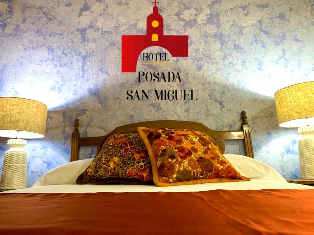 ein Bett mit Kissen und ein Schild an der Wand in der Unterkunft Hotel Posada San Miguel in Antigua Guatemala