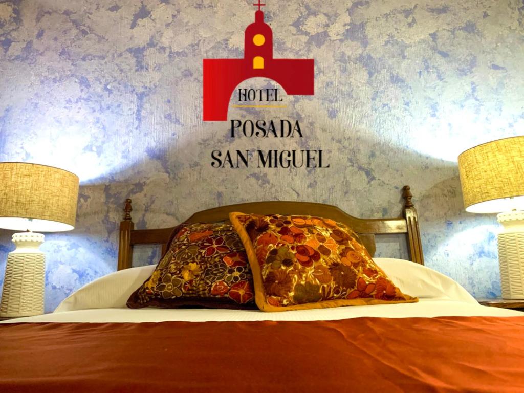 a bed with a pillow and a sign on a wall at Hotel Posada San Miguel in Antigua Guatemala