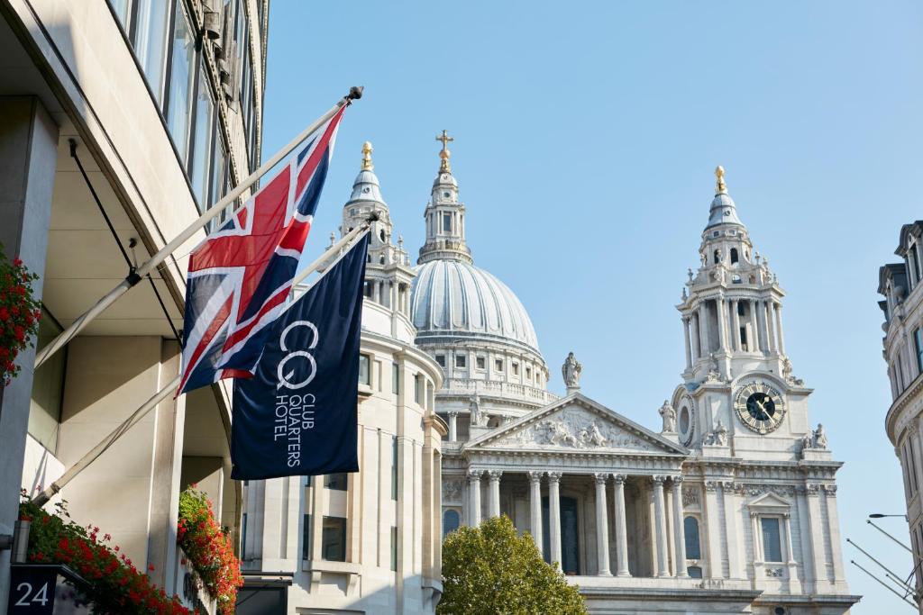 uma bandeira arvorando em frente a um edifício com uma catedral em Club Quarters Hotel St Paul's, London em Londres