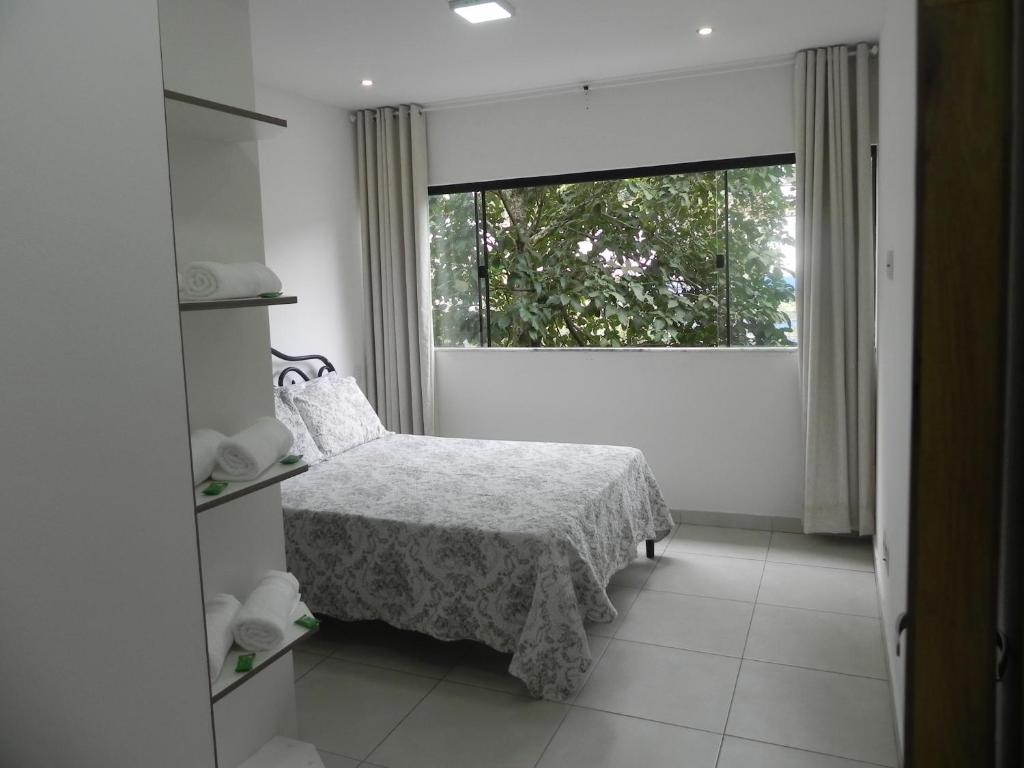 a bedroom with a bed and a large window at Aconchego e Requinte no Centro in Petrópolis