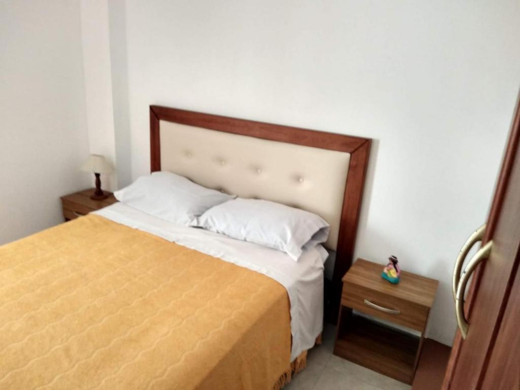 1 dormitorio con 1 cama con cabecero de madera y mesa en Brisas del Parque II en Salta