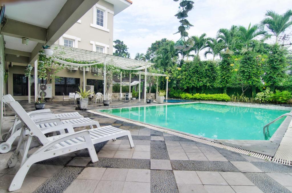 a swimming pool with two white chairs and a house at Country Heritage Hotel in Surabaya
