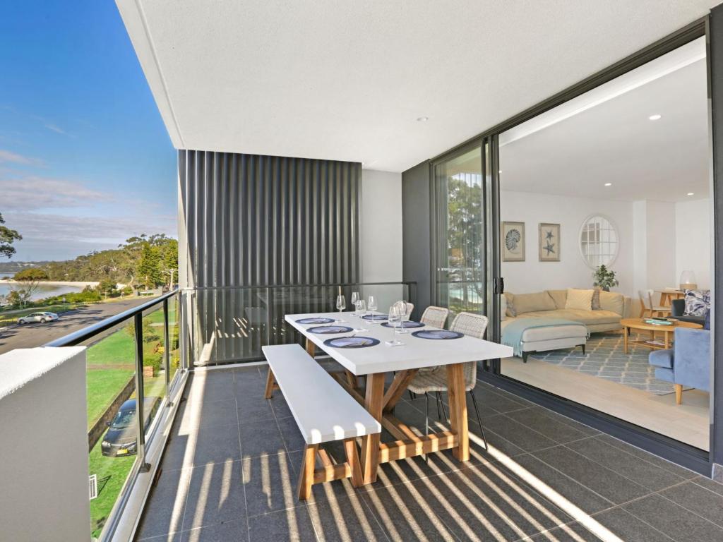 a living room with a table and chairs on a balcony at 204 on the Beach by Experience Jervis Bay in Huskisson