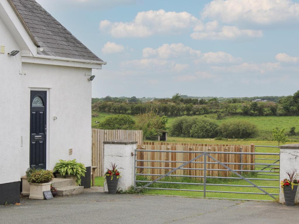 una casa blanca con una puerta y una valla en Llain Mai en Llangefni