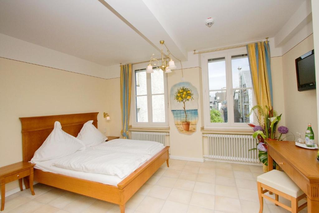 a bedroom with a bed and a desk and a window at XII Apostel Albergo in Cologne