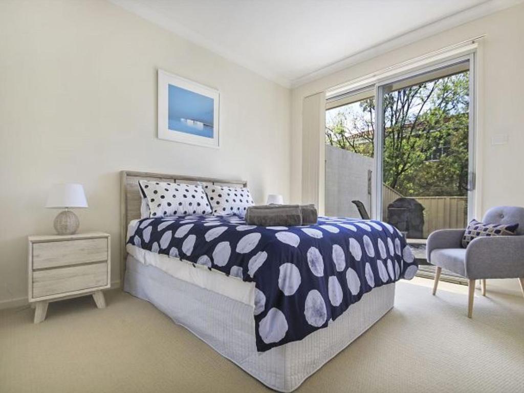 una camera da letto con un letto, una sedia e una finestra di Saltbush at Vincentia by Experience Jervis Bay a Vincentia