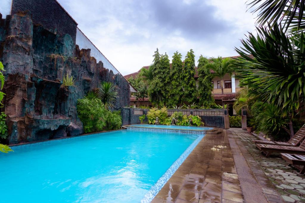 een zwembad voor een gebouw met blauw water bij Hotel Mahkota Plengkung by ecommerceloka in Banyuwangi