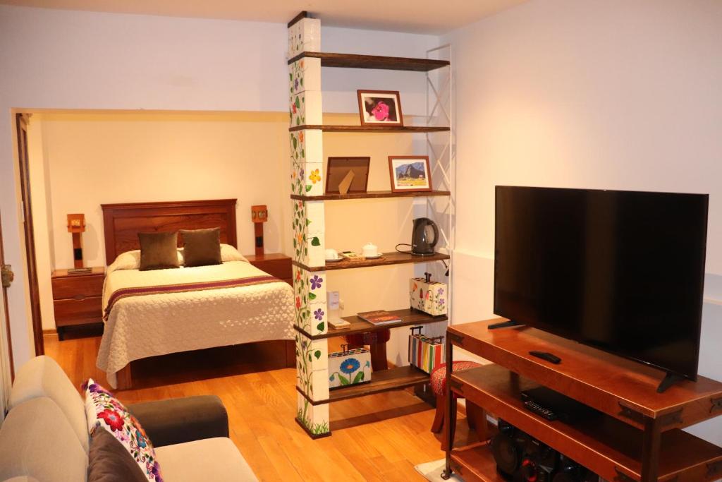 a living room with a bed and a television at Casa Rafaela in Cusco