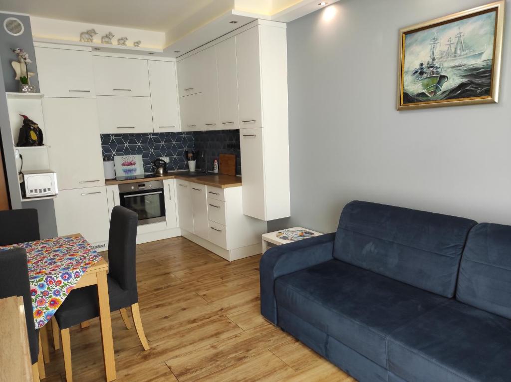 a living room with a blue couch and a table at Apartament Gdynia Oksywie z Tarasem , darmowy parking in Gdynia