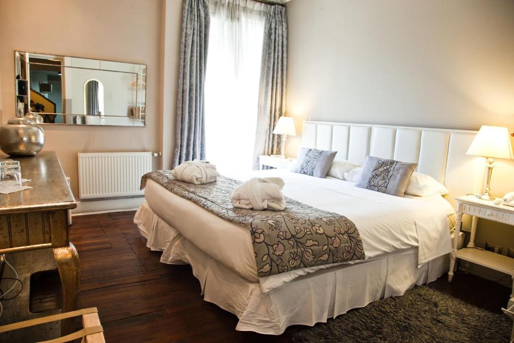 1 dormitorio con 1 cama blanca grande y espejo en Mito Casa Hotel, en Santiago