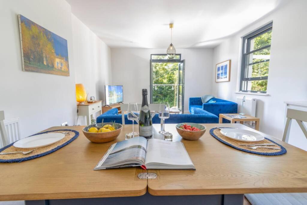 a wooden table with plates and bowls of fruit on it at 6 Oystercatcher Court - Stylish Apartment In Coastal Village Location in Stokeinteignhead