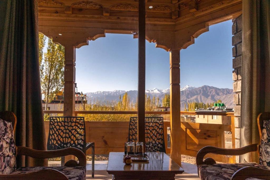 eine Veranda mit einem Tisch und Bergblick in der Unterkunft Adu's Eternal Comfort in Leh