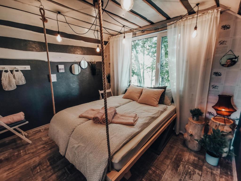 ein Schlafzimmer mit einem Schaukelbett und einem Fenster in der Unterkunft VIESU MĀJA KALNARUŠĶI in Lūšakrogs