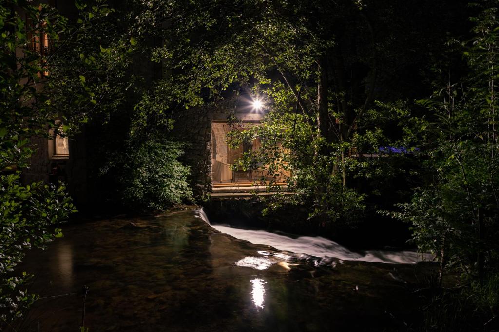 a house with a light in the window at night at La chapelle moulin traversée par l'eau jacuzzi piscine classé 5 étoiles in Bourg-Argental