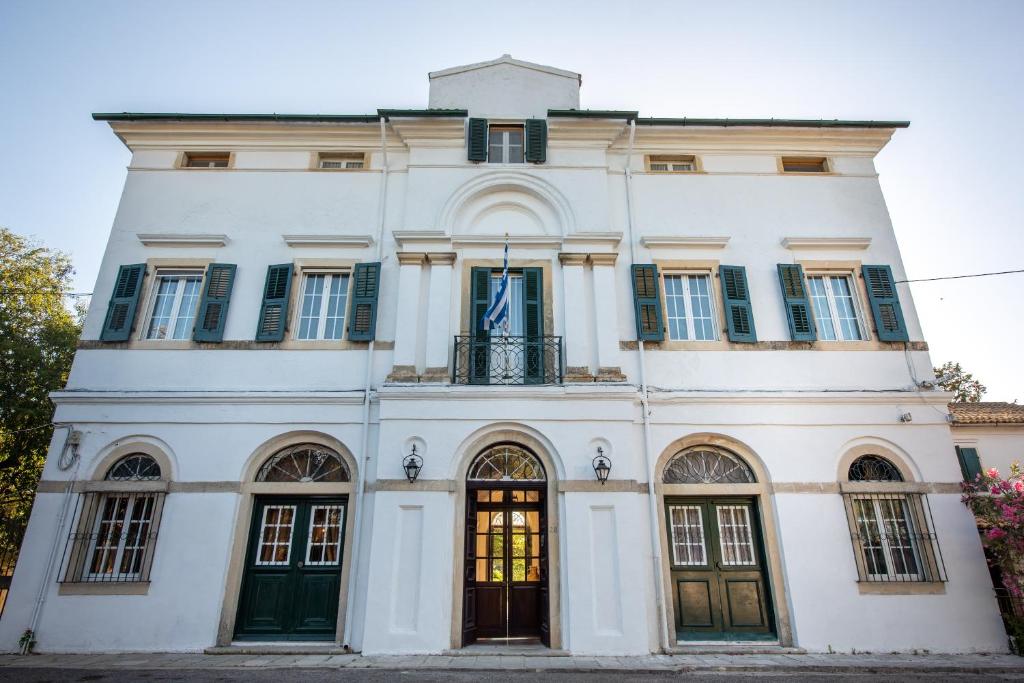 un edificio blanco con puertas y ventanas verdes en Archontiko Petrettini Boutique Hotel en Corfú