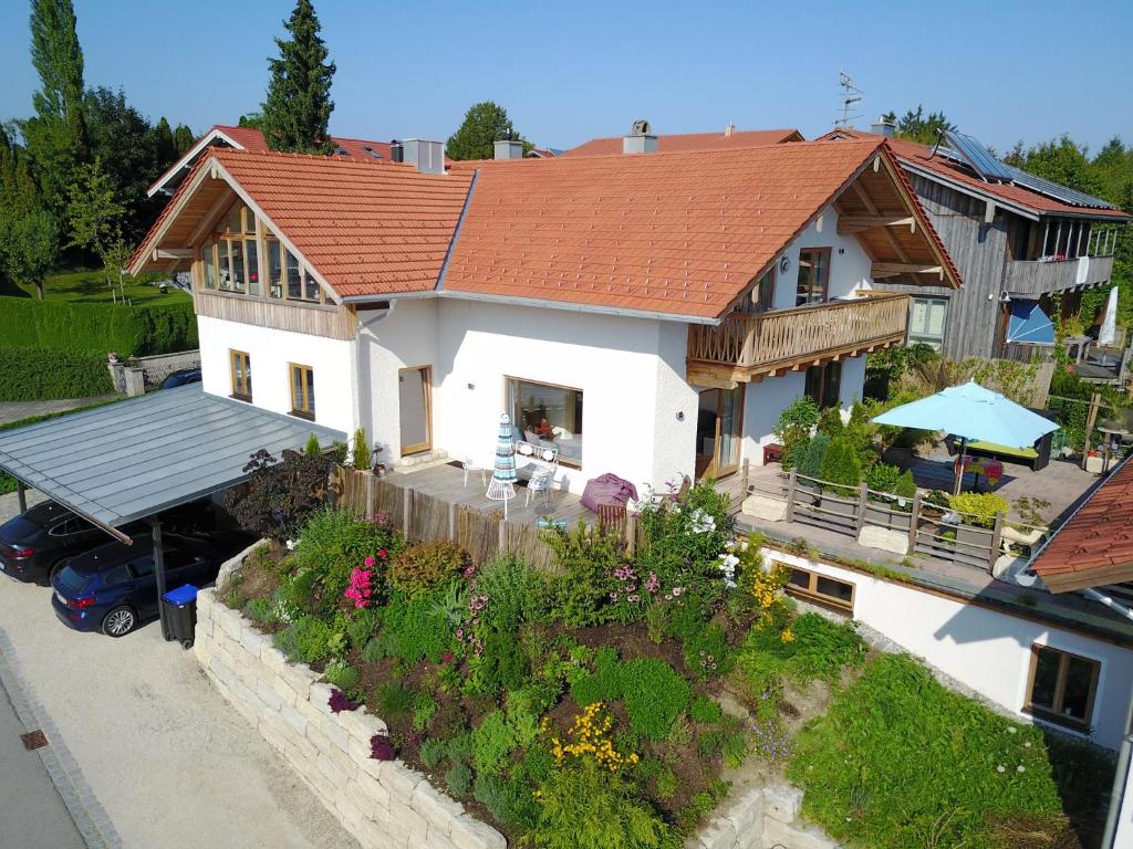 a white house with a red roof with a garden at Chiemsee Living in Chieming