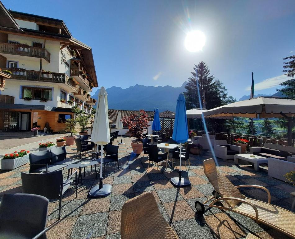 Monza Dolomites Hotel في موينا: مجموعة طاولات وكراسي مع مظلات