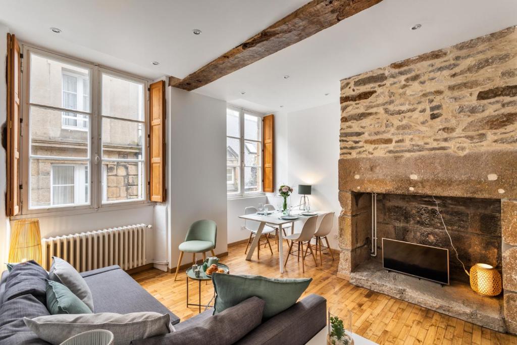 een woonkamer met een bank en een open haard bij Le Cerf Volant - une pépite à l'Intramuros in Saint-Malo