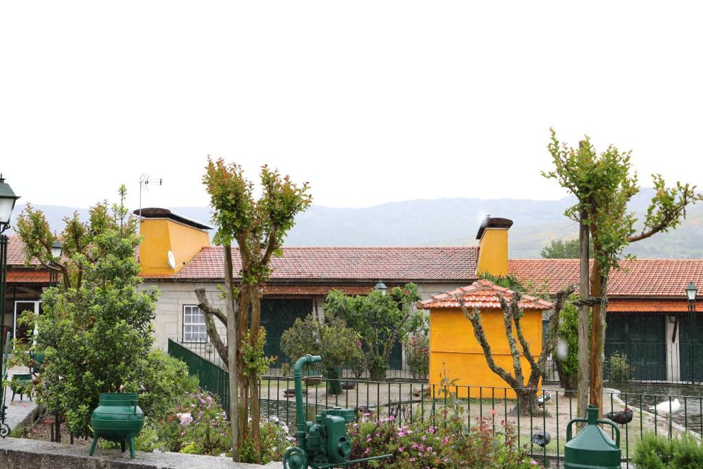 a yellow house with a fence and trees at Quinta dos Patos in Pinhanços