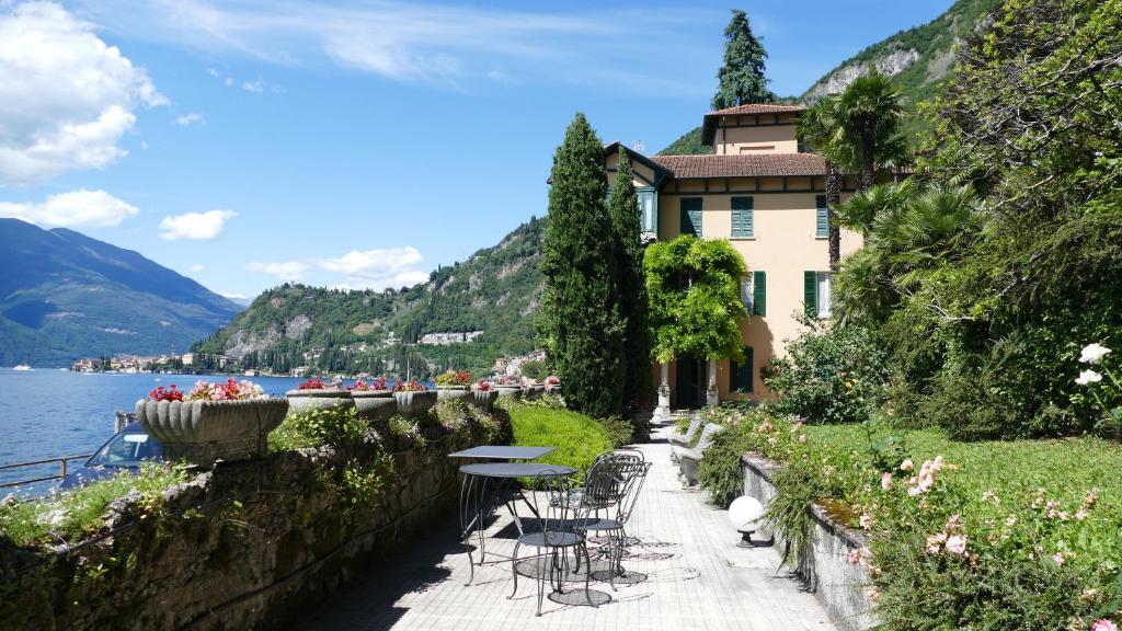 un bâtiment avec des tables et des chaises à côté de l'eau dans l'établissement Villa Reginella, à Varenna