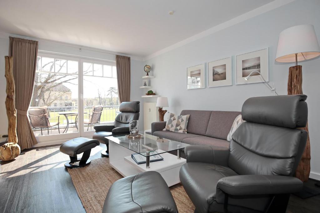 ein Wohnzimmer mit einem Sofa, Stühlen und einem Tisch in der Unterkunft Meeresblick Wohnung 104 - 4 Sterne DTV in Kühlungsborn