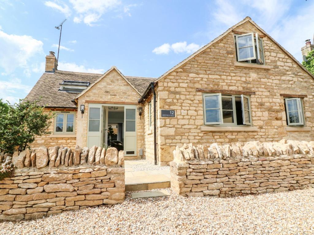 a stone house with a stone fence in front of it at 12 Manor Farm Close in Kingham