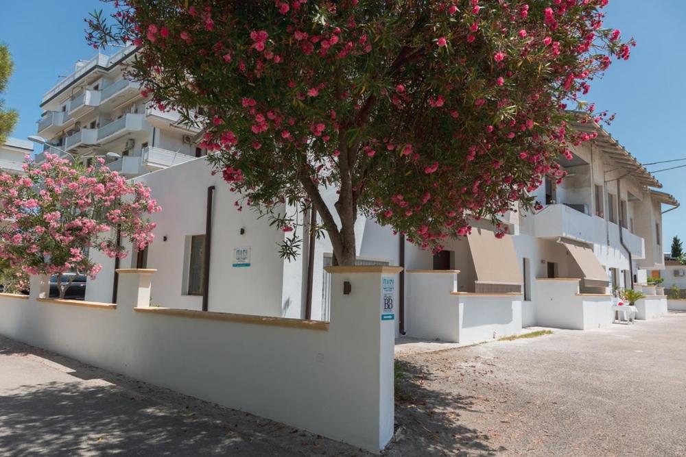een boom voor een wit gebouw met roze bloemen bij B&B OASI SUL MARE San Salvo Marina in San Salvo