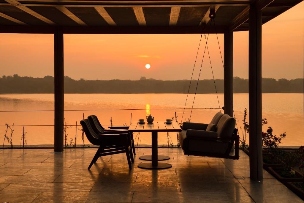 - une table et des chaises sur une terrasse avec vue sur le coucher du soleil dans l'établissement RAAS Chhatrasagar, Nimaj, District Pali, à Pāli
