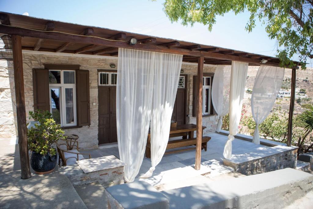 un porche con cortinas blancas y un banco en Skinos House en Vari