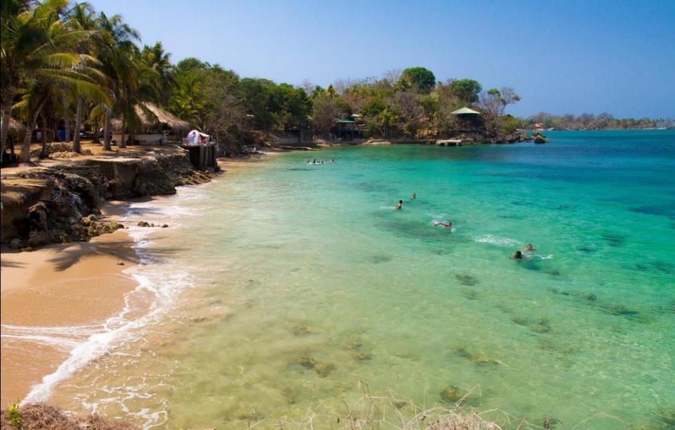 a group of people swimming in the water at a beach at Private Beach house Maloka Surf in Isla Fuerte
