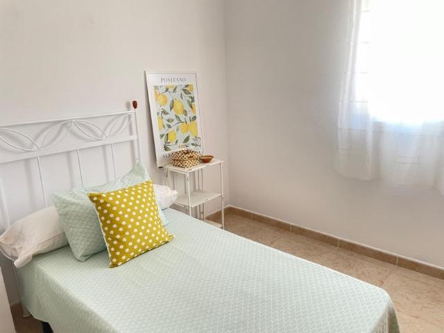 Dormitorio blanco con cama con almohada amarilla en CASA LIMÓN, en Cunit