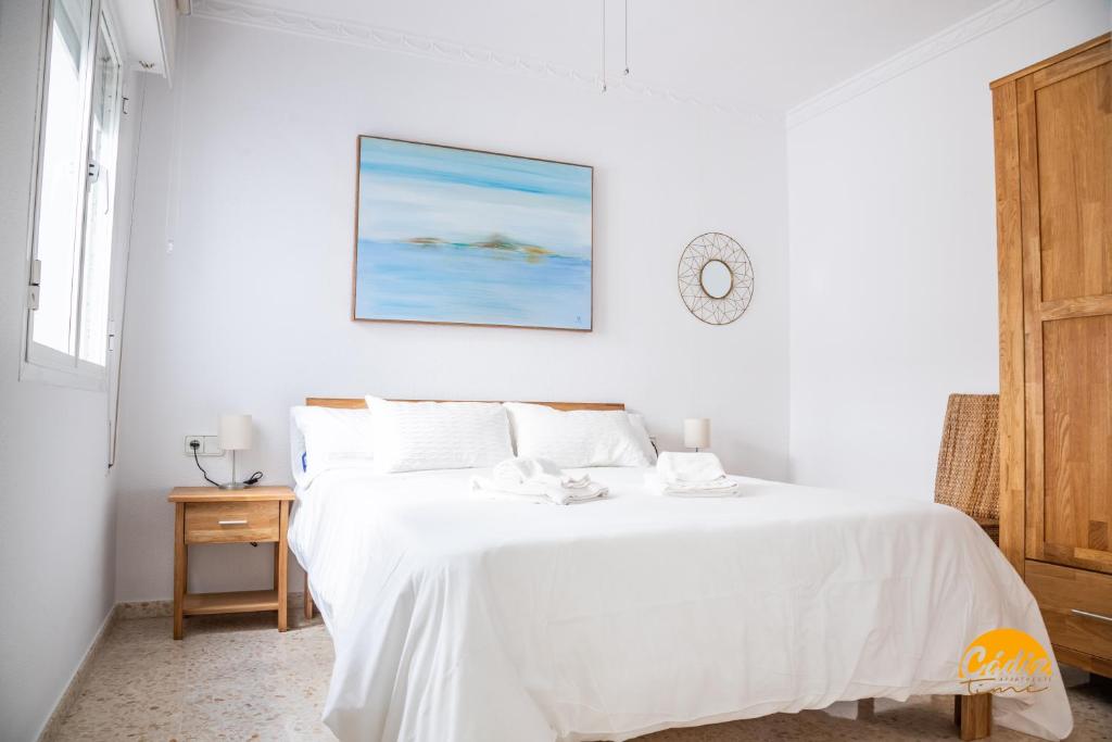 een witte slaapkamer met een groot bed met witte lakens bij Casa Genoves by Cadiz Time in Cádiz