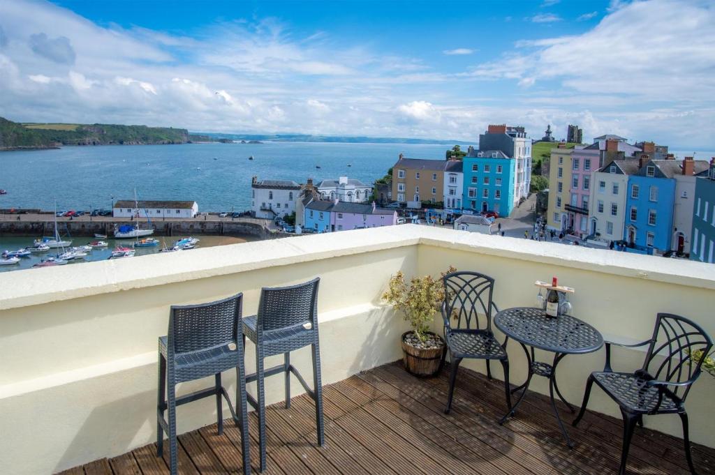 a balcony with chairs and a table with a view of the water at St Julians View - 1 Bedroom Apartment - Tenby in Tenby
