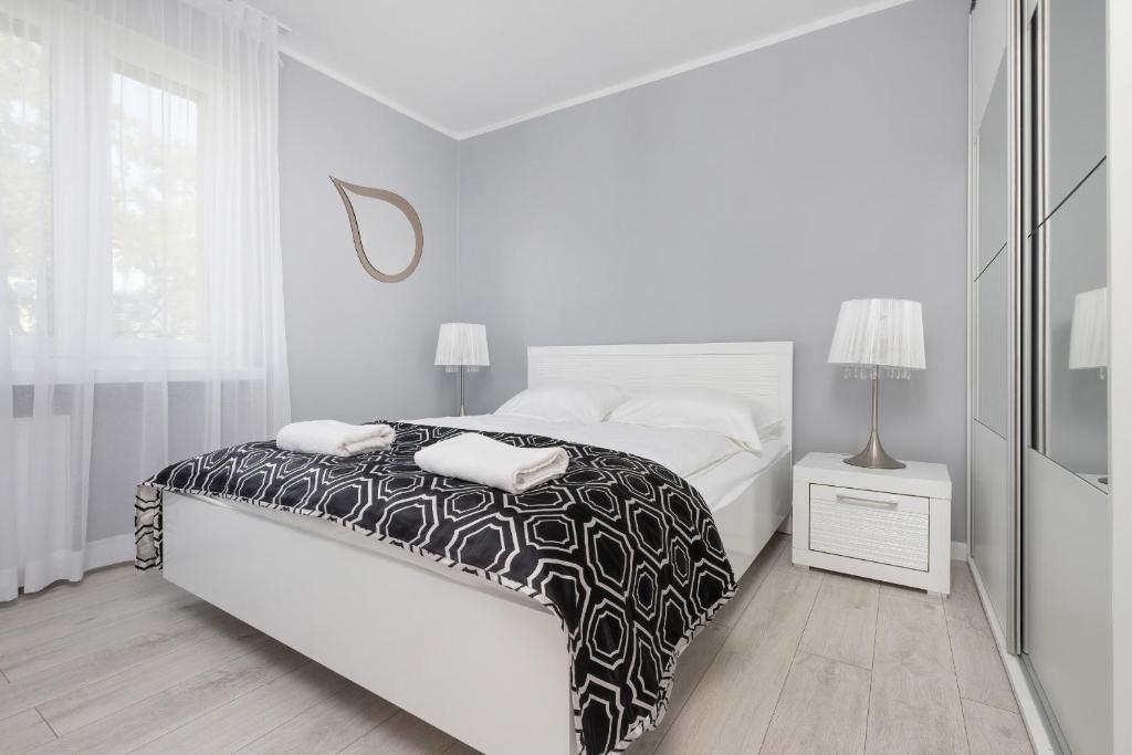 a white bedroom with a black and white bed at Przymorze Apartment Jagiellońska by Renters in Gdańsk